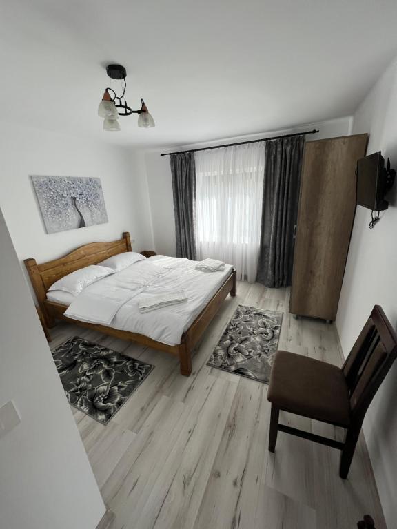 a bedroom with a bed and a chair and a window at Cazare Nely in Novaci-Străini