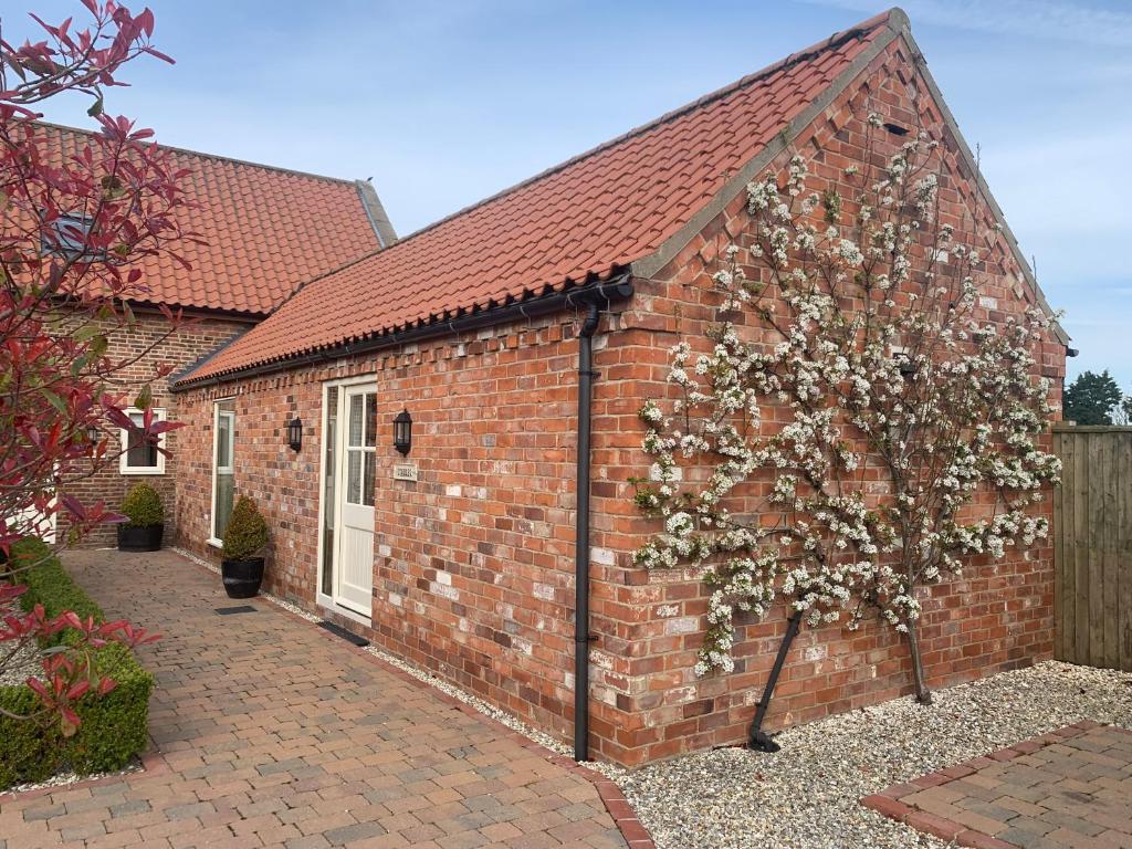 a red brick building with a tree in front of it at Meals Farm Holiday Cottages - The Stables in North Somercotes