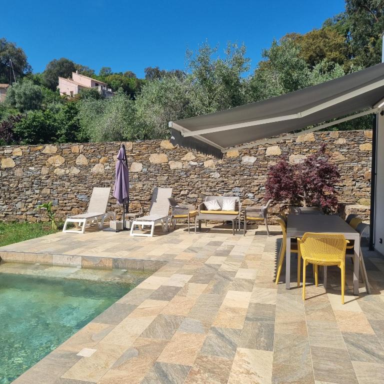 a patio with chairs and tables next to a pool at Rez de villa avec piscine, wifi, jardin clôturé in Penta-di-Casinca