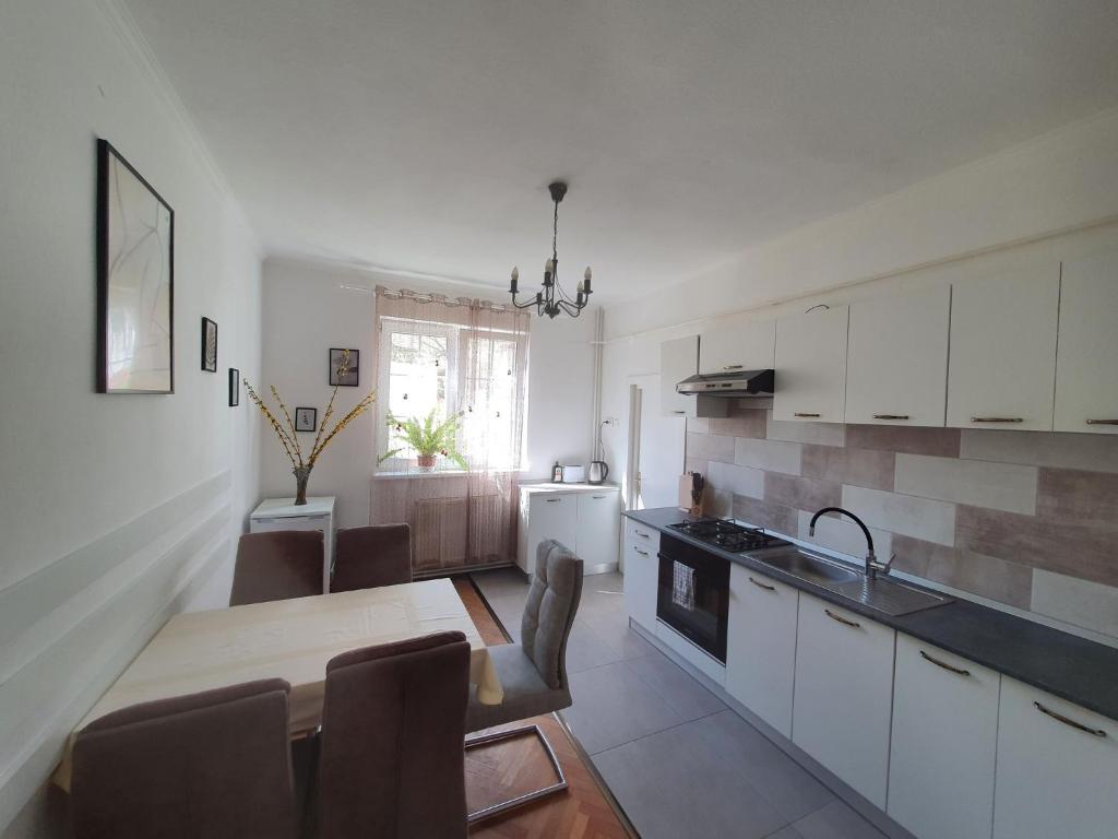 een keuken met witte kasten en een tafel en stoelen bij Andrea apartman in Sfântu-Gheorghe