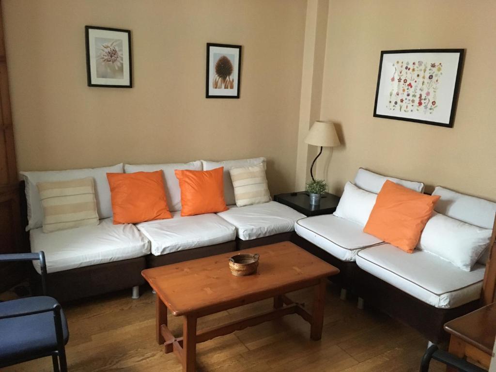 ein Wohnzimmer mit einer weißen Couch und orangefarbenen Kissen in der Unterkunft Apartamento Centro Ciudad Ronda in Ronda