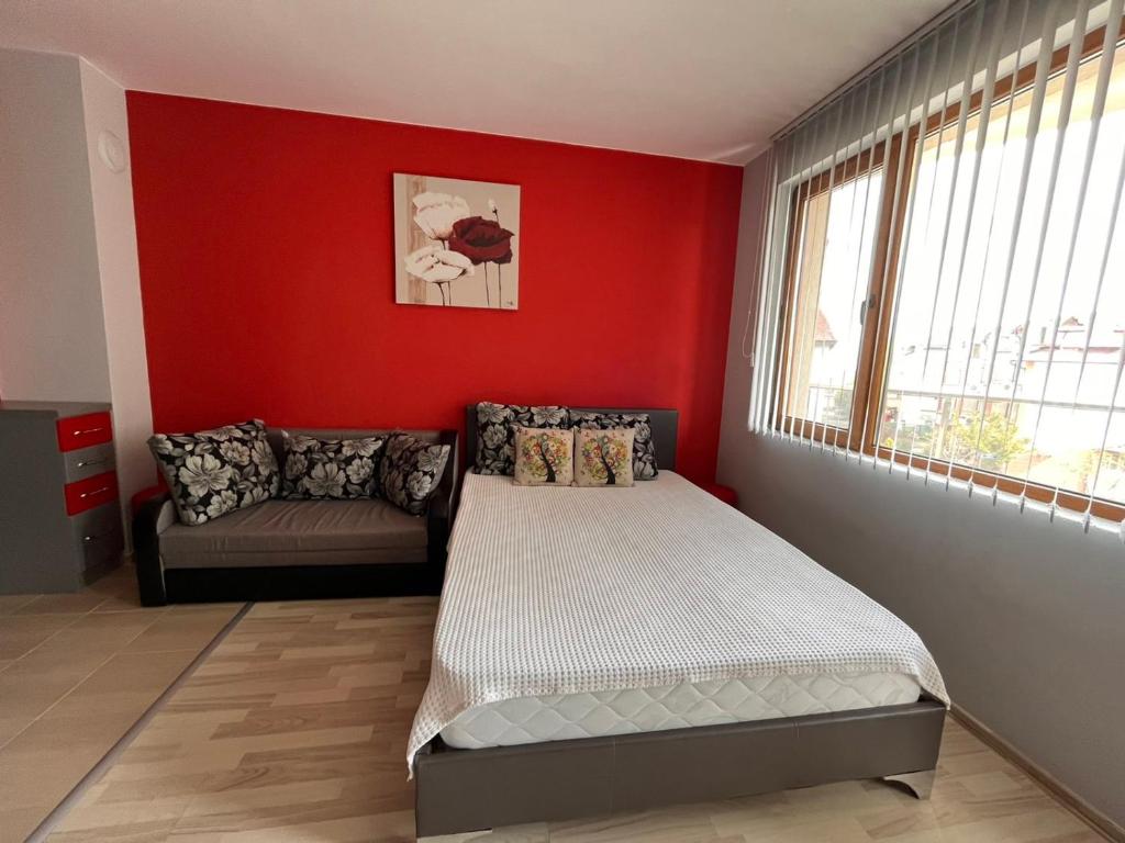 Dormitorio rojo con cama y sofá en Sirena Holidays, en Ravda