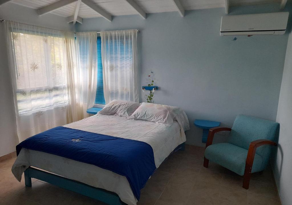 a bedroom with a bed and a blue chair at HOTEL CAMPESTRE - BRUGMANSIA - Fincahotel in Montenegro