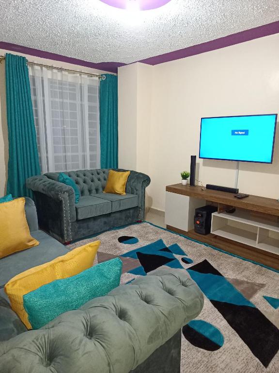 a living room with a couch and a flat screen tv at Executive 1-bedroom, in Ruiru in Nairobi