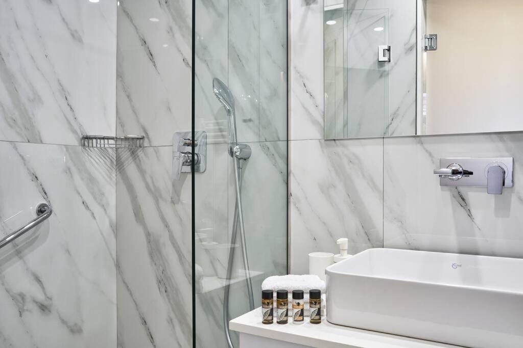 un bagno bianco con doccia e lavandino di Spacious 2bd Apt in Prime Location next to Divani ad Atene
