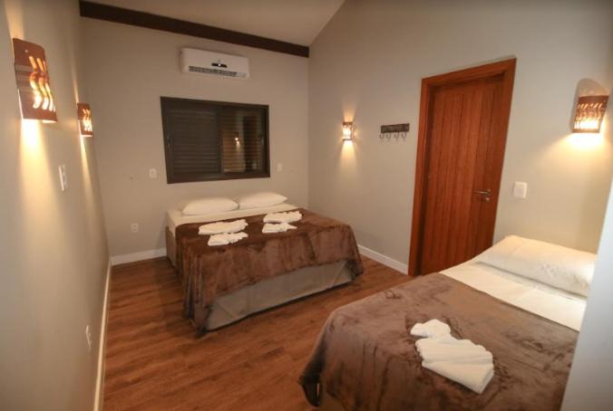 Habitación de hotel con 2 camas y ventana en Suítes Novas no Coração de Bonito en Bonito