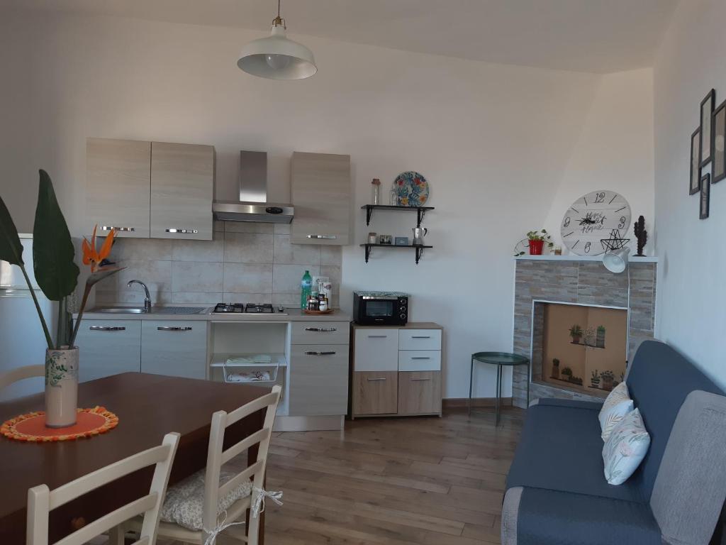 een keuken en een woonkamer met een tafel en een blauwe bank bij Sa Calla Manna in Portoscuso