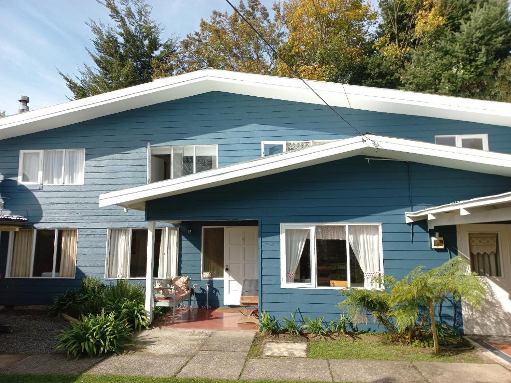 una casa azul con techo blanco en Hostería Alemana en Villarrica