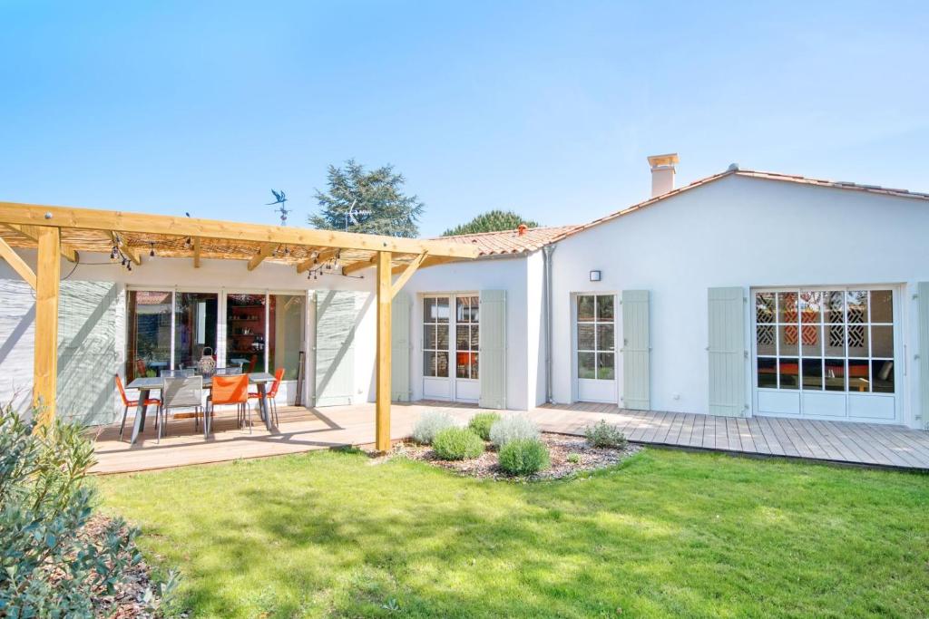 Dieses weiße Haus verfügt über eine Terrasse mit einem Tisch und Stühlen. in der Unterkunft "NOLA" Charmante Villa contemporaine et spacieuse in La Flotte