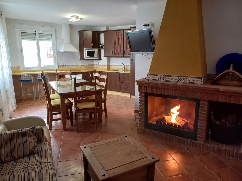 a living room with a fireplace and a table with chairs at Casa el corzo in La Iruela