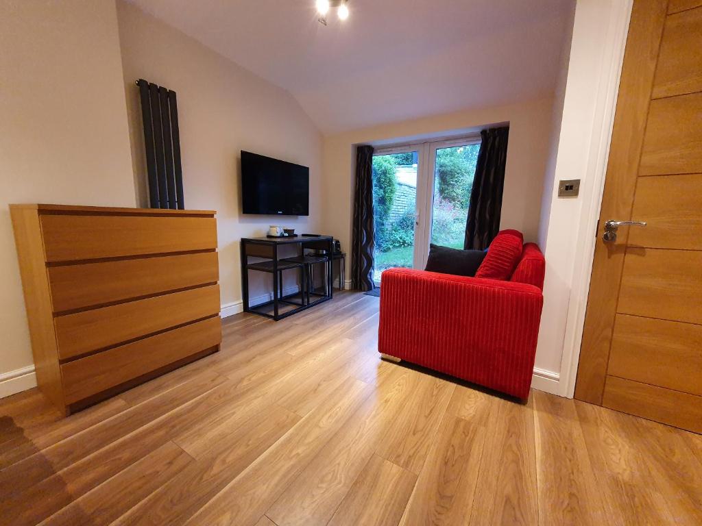 a living room with a red chair and a television at Old School House Studio in Stetchworth