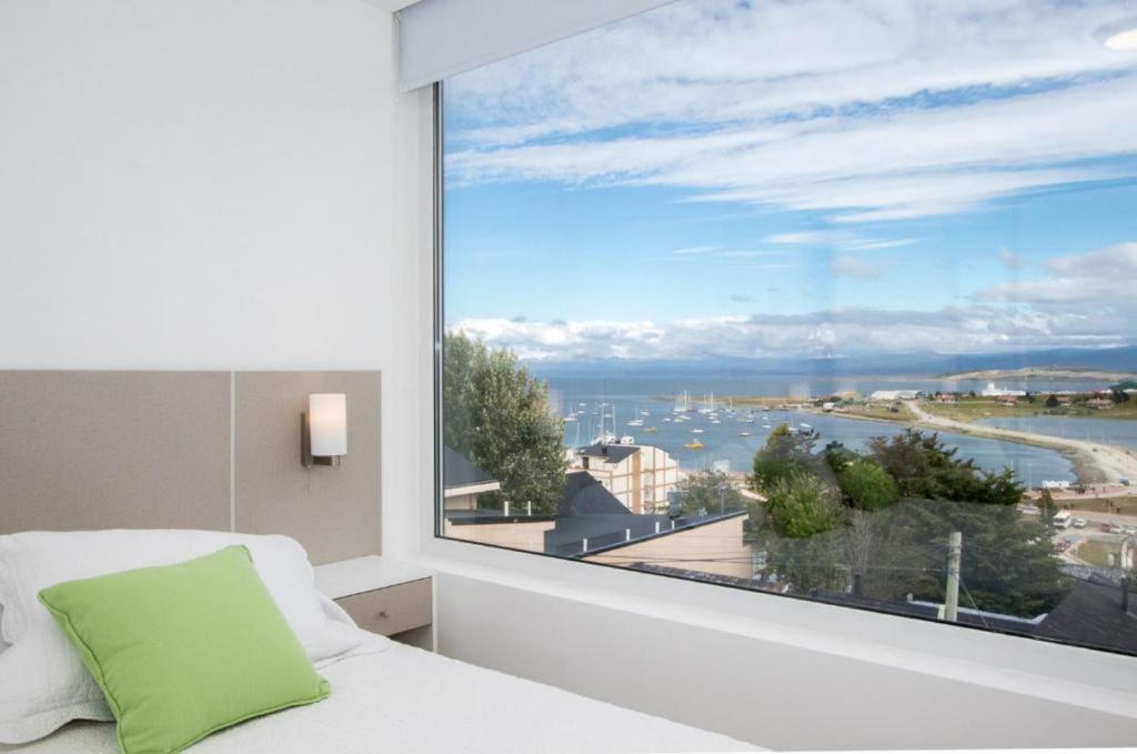 a bedroom with a large window with a view of the water at Pacífico Apartamentos Centro in Ushuaia