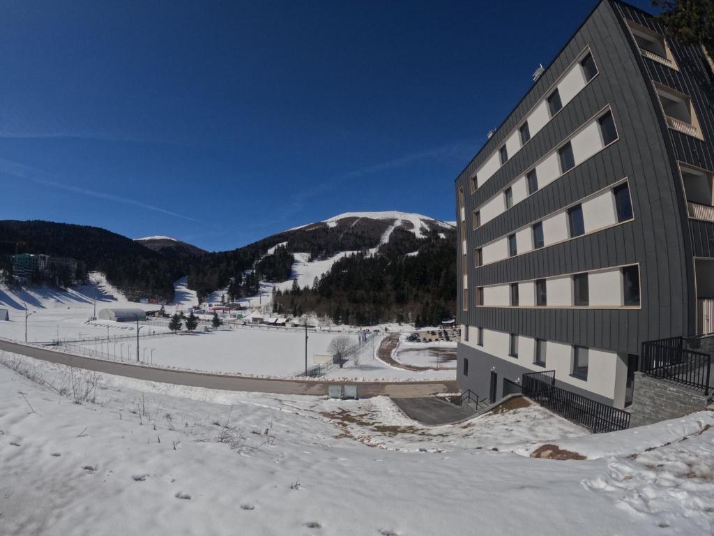 a building in the snow next to a mountain at Whitehouse apartment in Bjelašnica