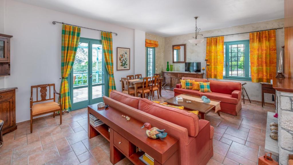 een woonkamer met twee rode banken en een tafel bij bougainvilla in Fodele