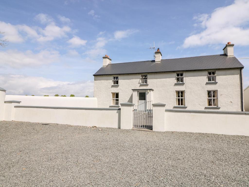 a large white house with a white wall at Grange Farmhouse in Fethard on Sea