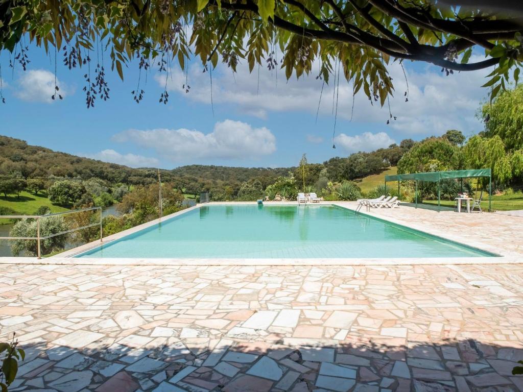 a swimming pool in a villa with a mountain in the background at Idyllic Farmhouse in Montemor o Novo with Swimming Pool in Montemor-o-Novo
