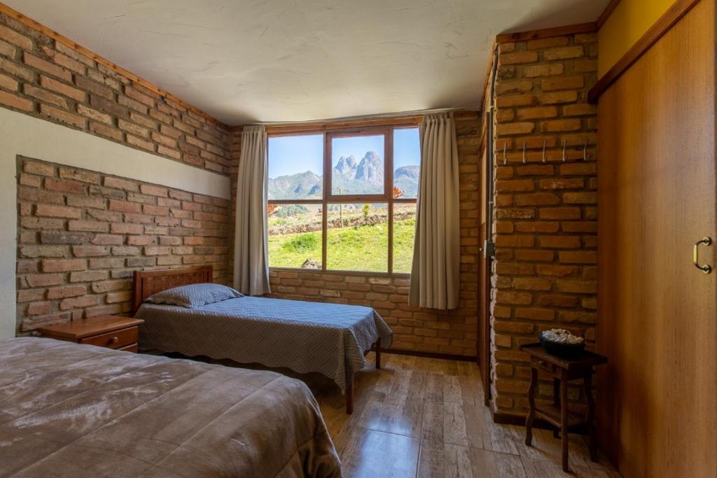 a bedroom with two beds and a brick wall at Reserva Três Picos Chalés in Nova Friburgo