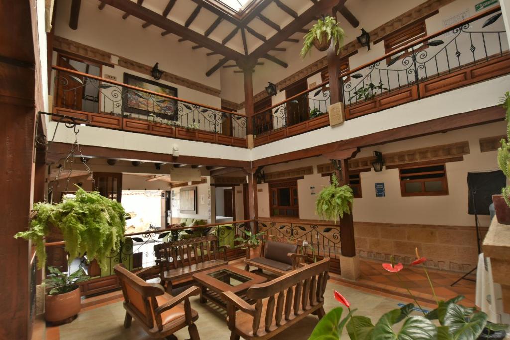 a large living room with wooden furniture and plants at Hotel Jardines De La Villa in Villa de Leyva