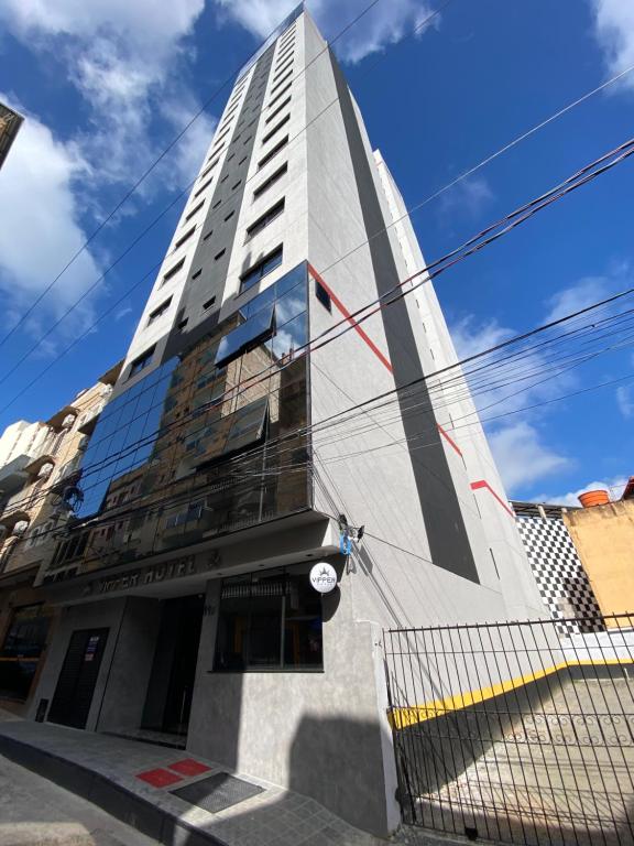 ein hohes weißes Gebäude mit einem Zaun davor in der Unterkunft VIPPER Hotel in Aparecida