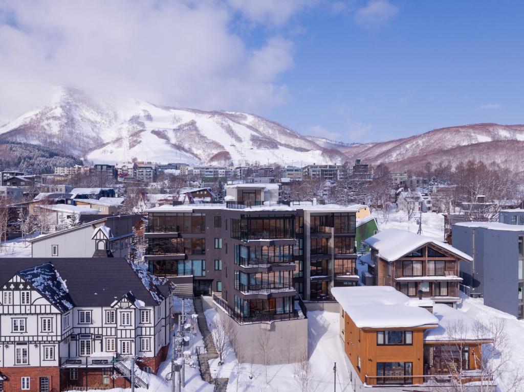 een stad met sneeuw bedekte bergen op de achtergrond bij Aspect Luxury Apartments by H2 Life in Kutchan