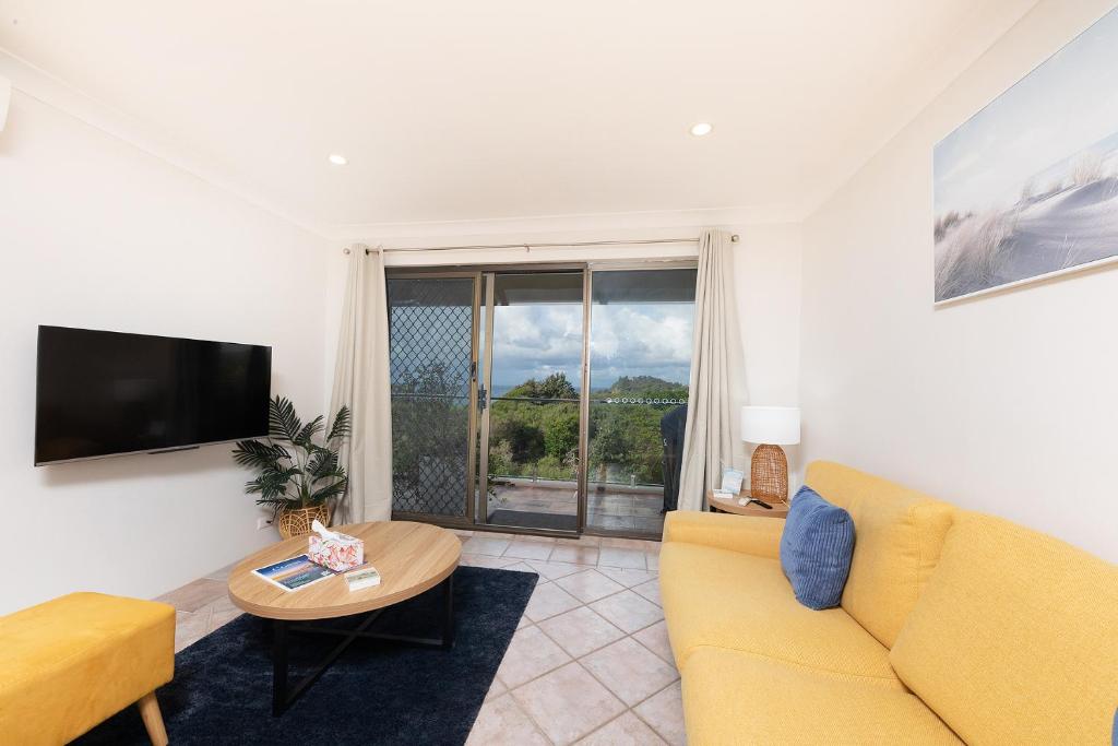een woonkamer met een gele bank en een tafel bij Oceancrest 15 in Forster