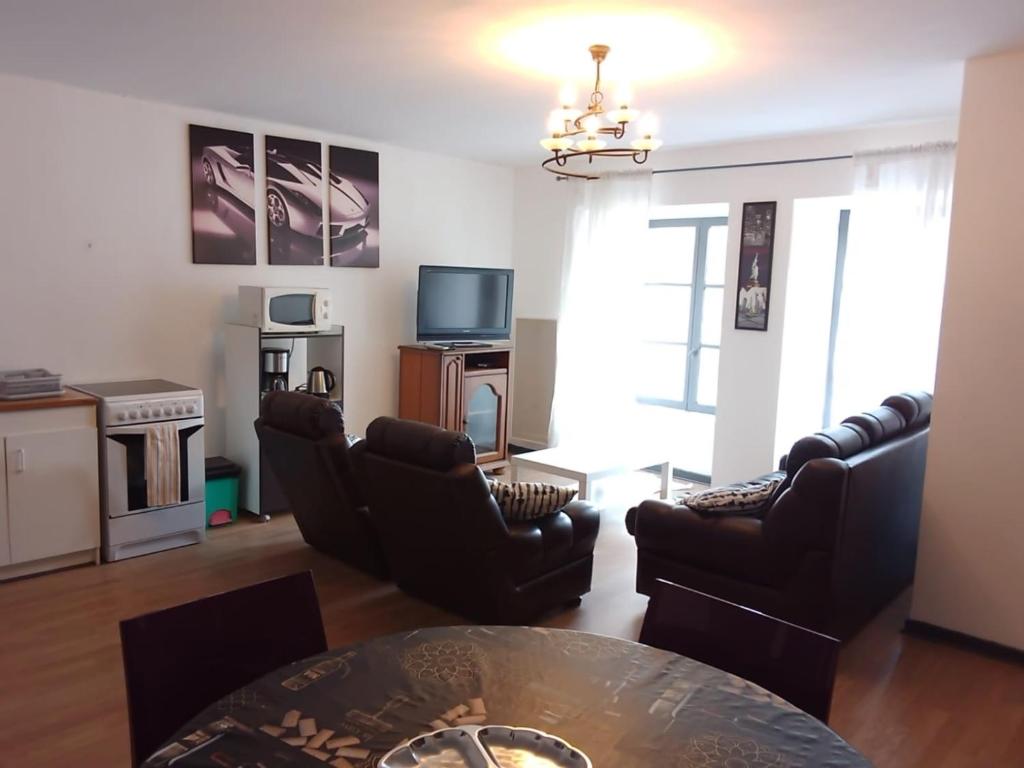 a living room with leather chairs and a table at Grand Appartement avec stationnement in Champlitte-et-le-Prélot