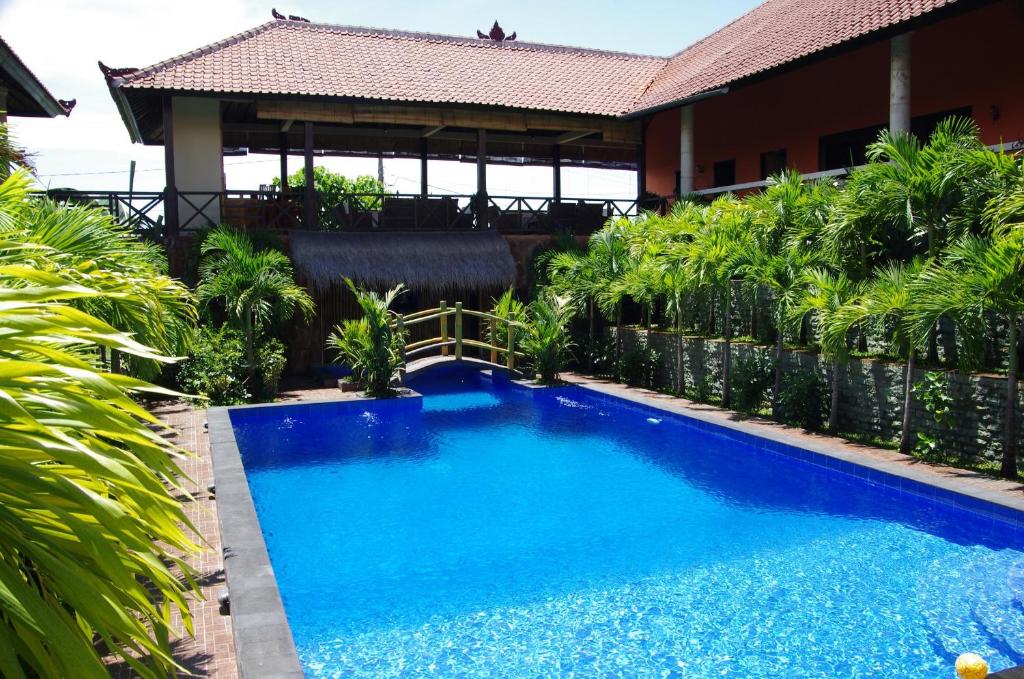 a blue swimming pool in front of a building at Tulamben Backpacker in Tulamben