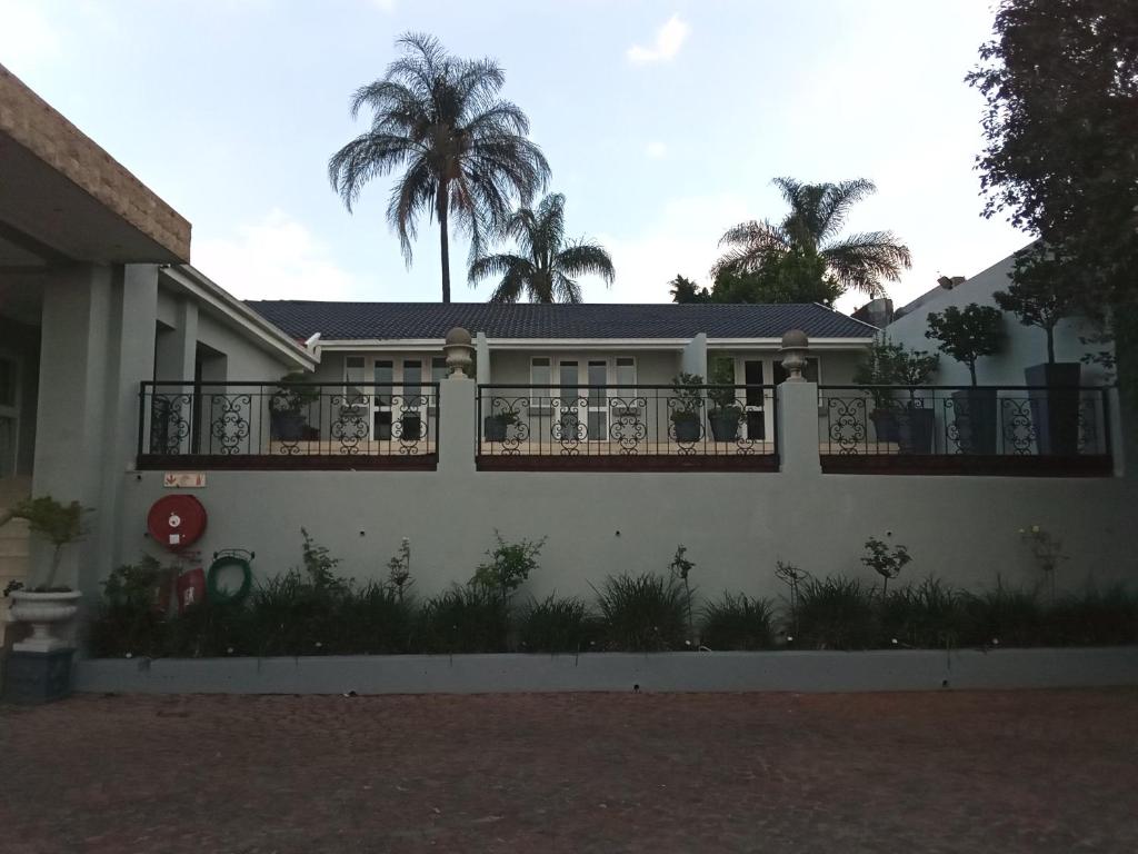a house with a fence and palm trees in the background at 131 on Herbert Baker Boutique Hotel in Pretoria