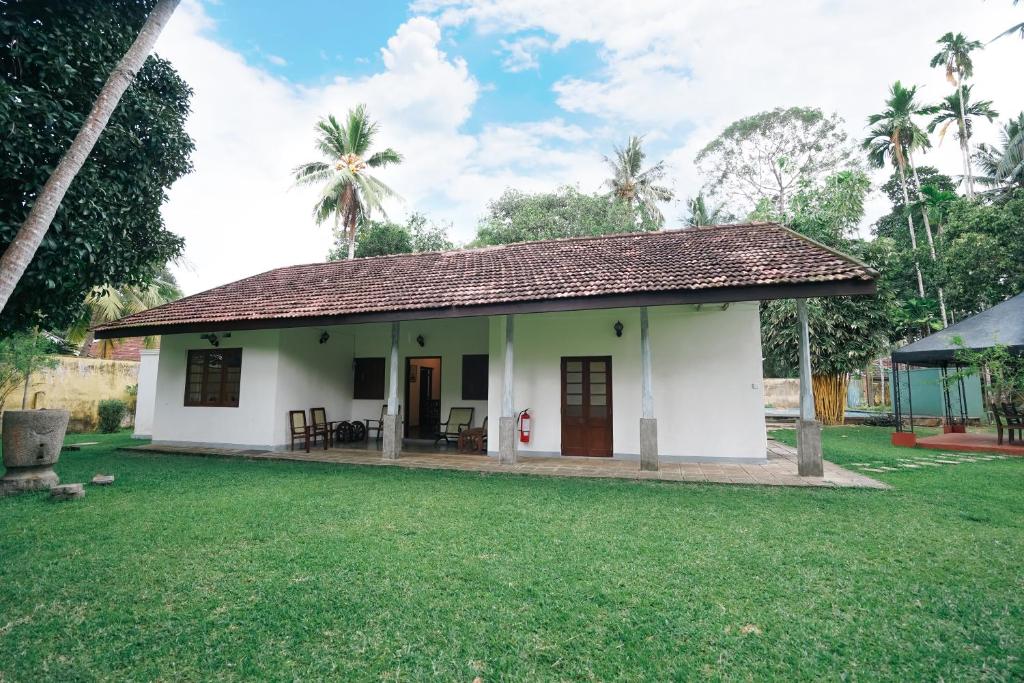 une petite maison blanche avec une cour d'herbe dans l'établissement Gedara Villa, à Kalutara