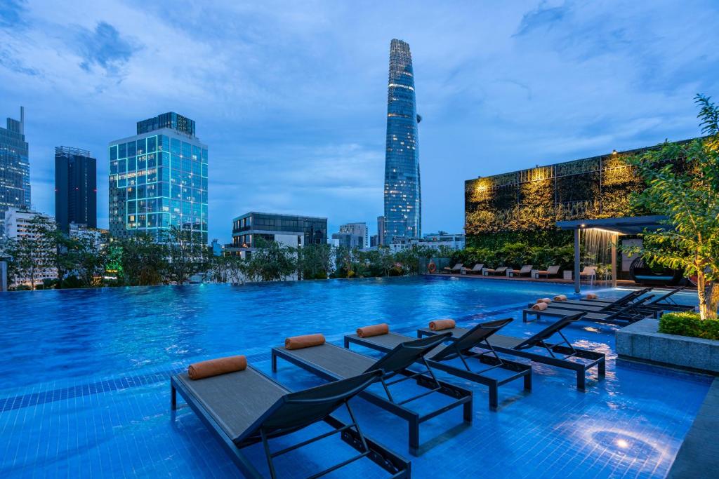 a pool with chairs and a city skyline at night at Fusion Original Saigon Centre in Ho Chi Minh City