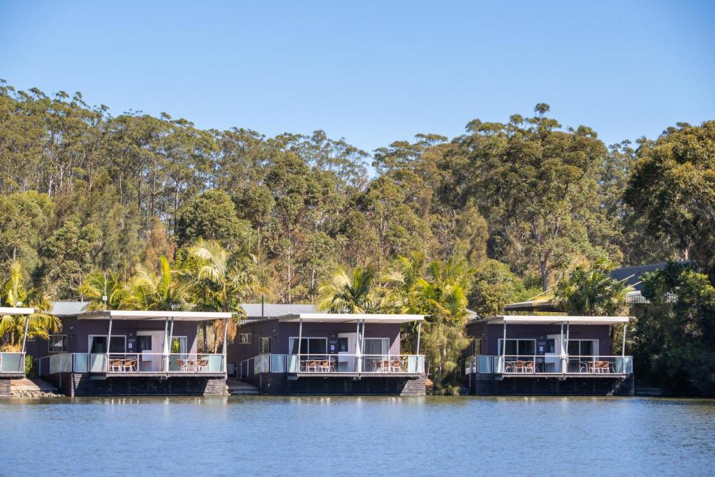 three houses on the water with trees in the background at Ingenia Holidays Lake Conjola in Conjola