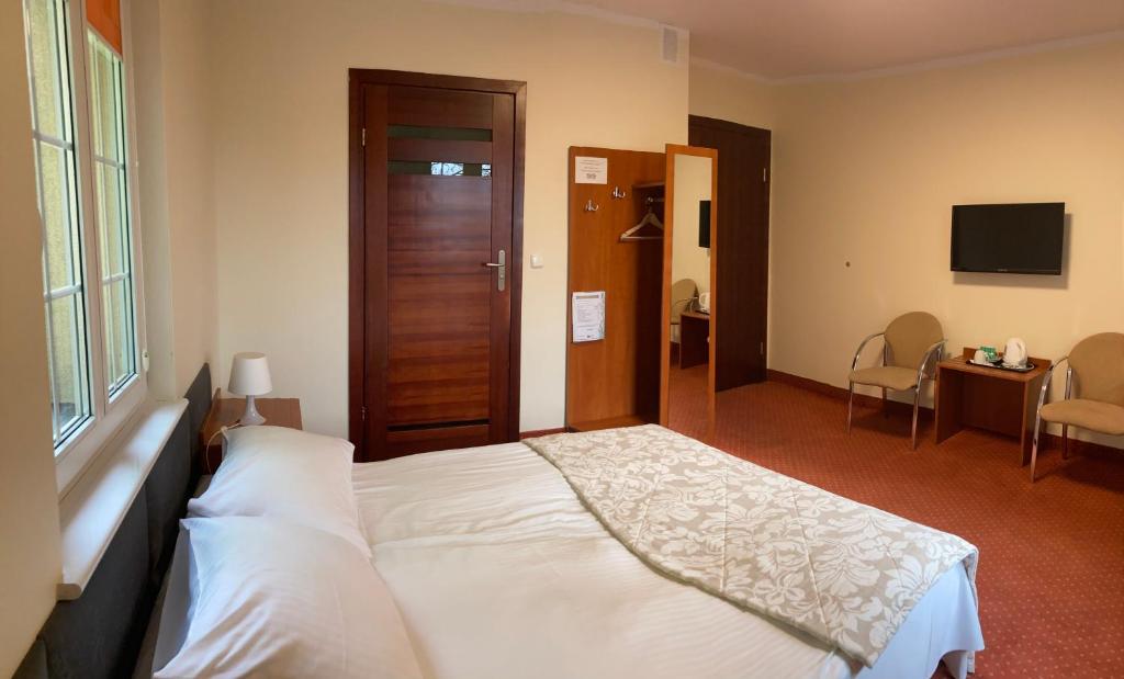 a hotel room with a bed, desk, and chair at Hotel Gryf in Kościerzyna