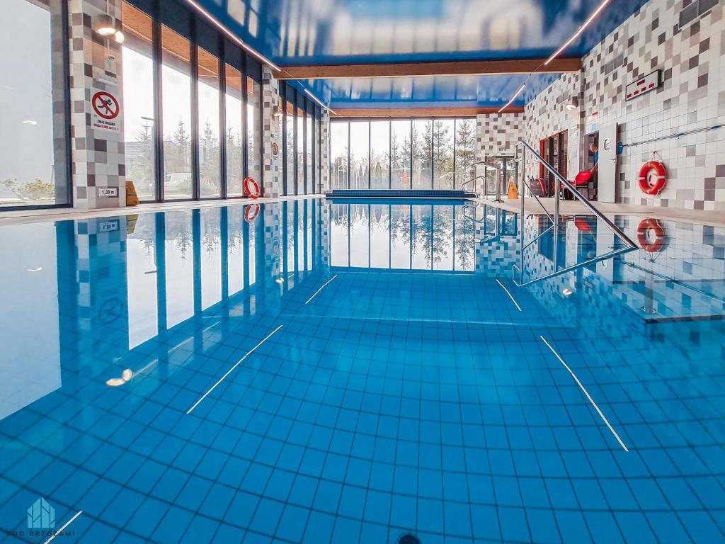 an empty swimming pool with blue tile floors and windows at Pod Brzozami Apartamenty 5 Mórz in Ustronie Morskie