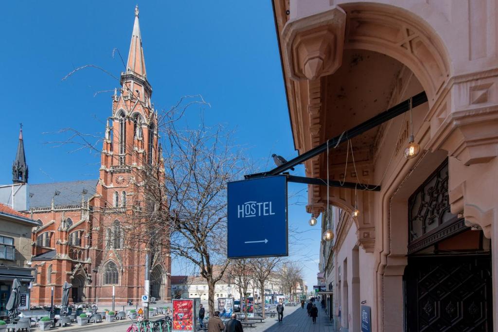 una señal en el lateral de un edificio con una torre de reloj en Hostel OS en Osijek