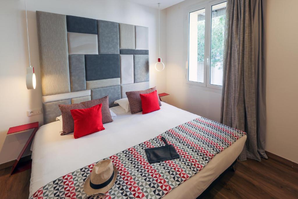 a bedroom with a large bed with red pillows at Hôtel Méditerranée in Calvi