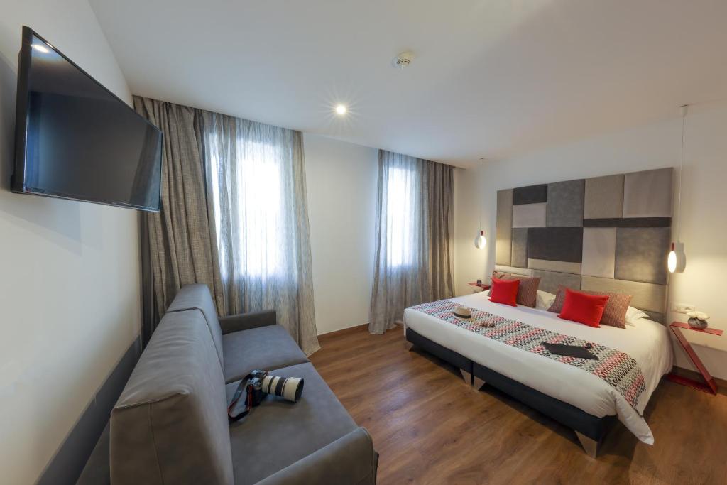 a hotel room with a bed and a couch at Hôtel Méditerranée in Calvi