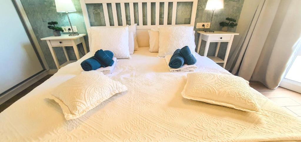 un grande letto bianco con due cuscini blu sopra di Harmony Apartments ad Arona