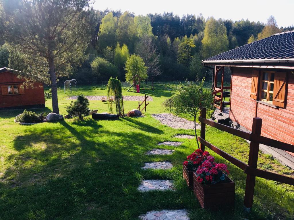 un patio con una casa y una valla y flores en Domki letniskowe przy lesie - "U Łastka", en Bartołty Wielkie