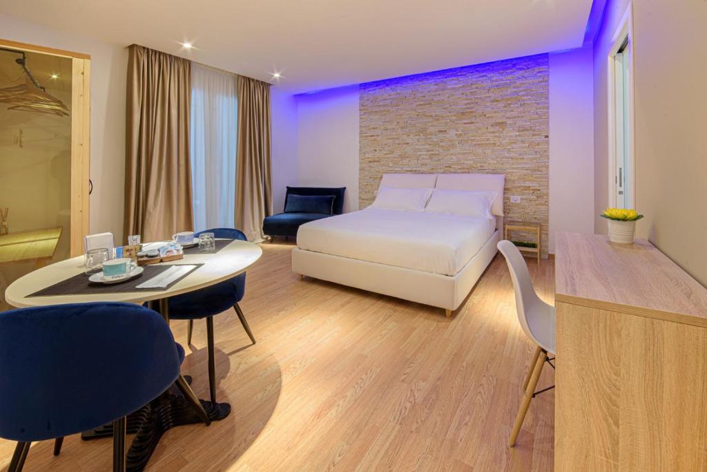 una camera d'albergo con letto, tavolo e sedie di Aminta - Rooms & Wellness ad Andria