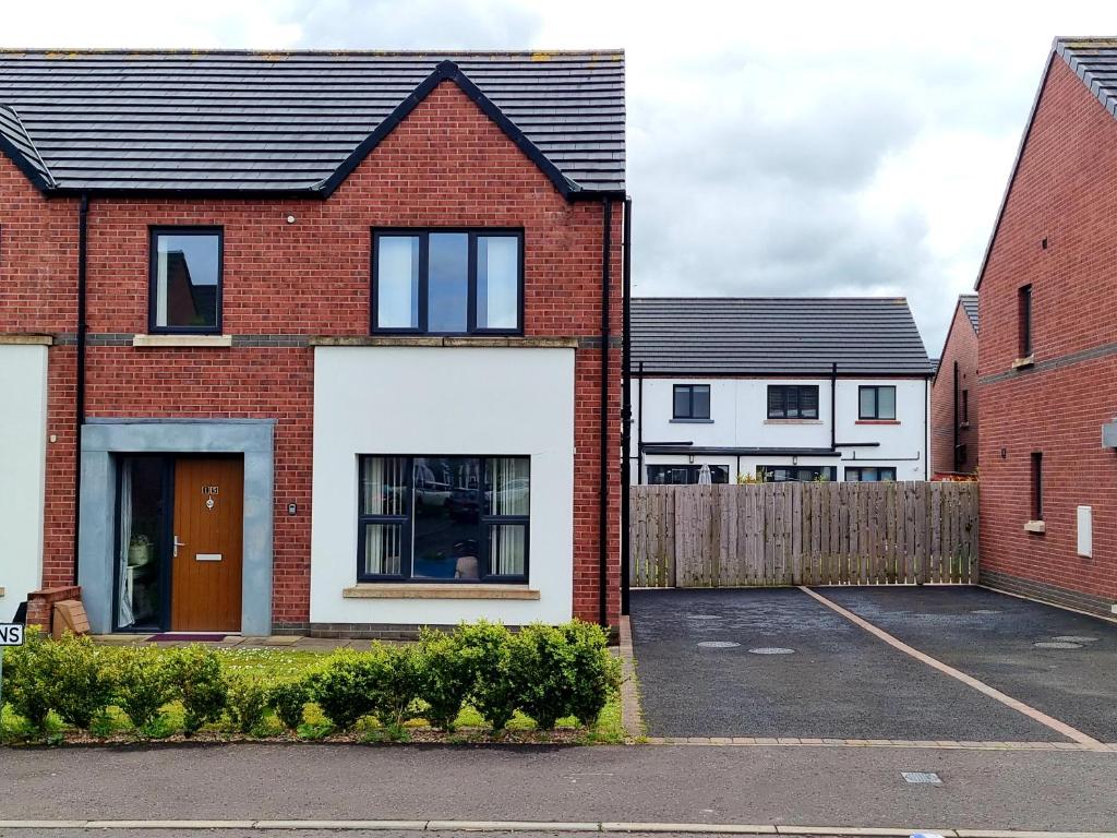 a red brick house with a parking lot at Modern 3 bedroom semi detached home in Limavady