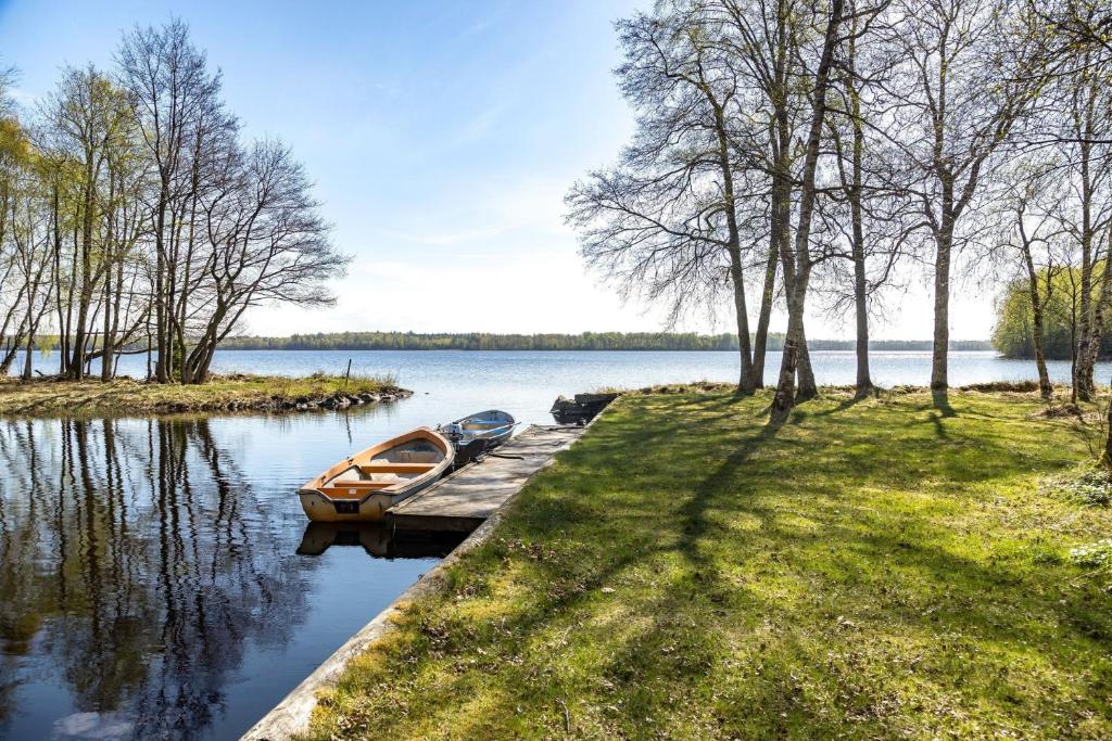 Ein Boot liegt an einem Dock auf einem See. in der Unterkunft Holiday house with lake view of Bolmen in Bolmsö