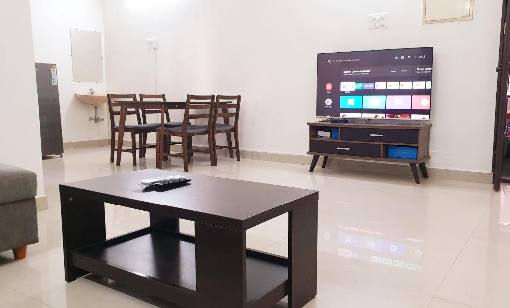 a living room with a table and a tv at Chippy Apartments No.27 in Chennai