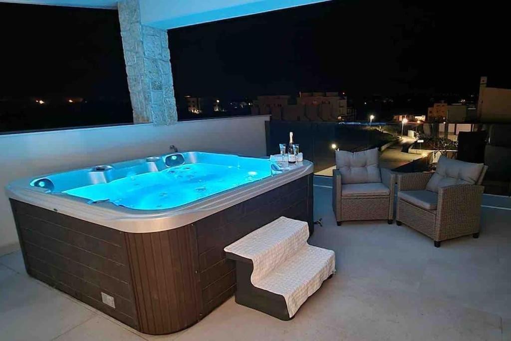 uma banheira de hidromassagem na varanda à noite em Gemütliches Ferienhaus mit Whirlpool & Dachterrasse em Privlaka