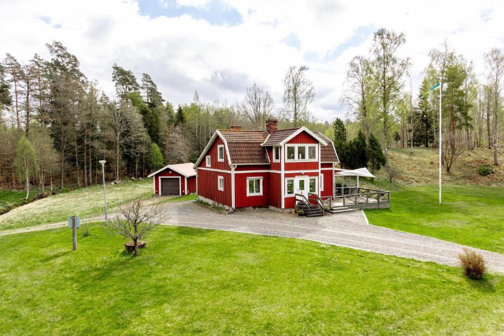 ein rotes Haus auf einem üppigen grünen Feld in der Unterkunft Holiday house with fantastic location and 300 m to its own lake shore in Rydaholm