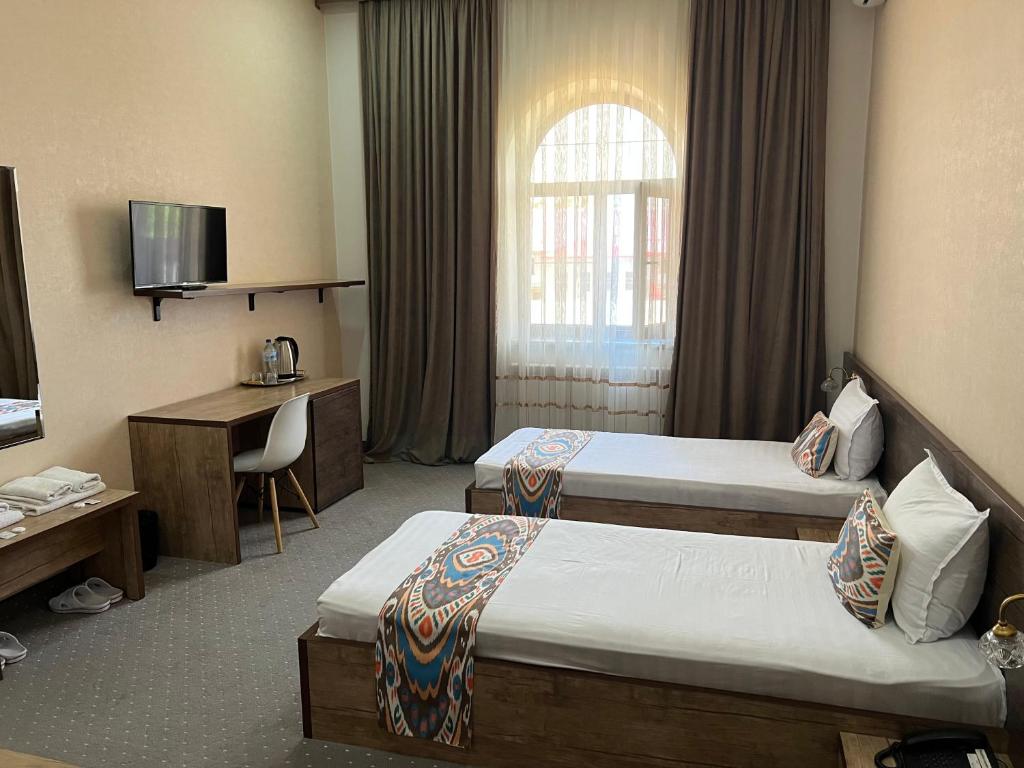 a hotel room with two beds and a desk at Mahmud Hotel in Samarkand