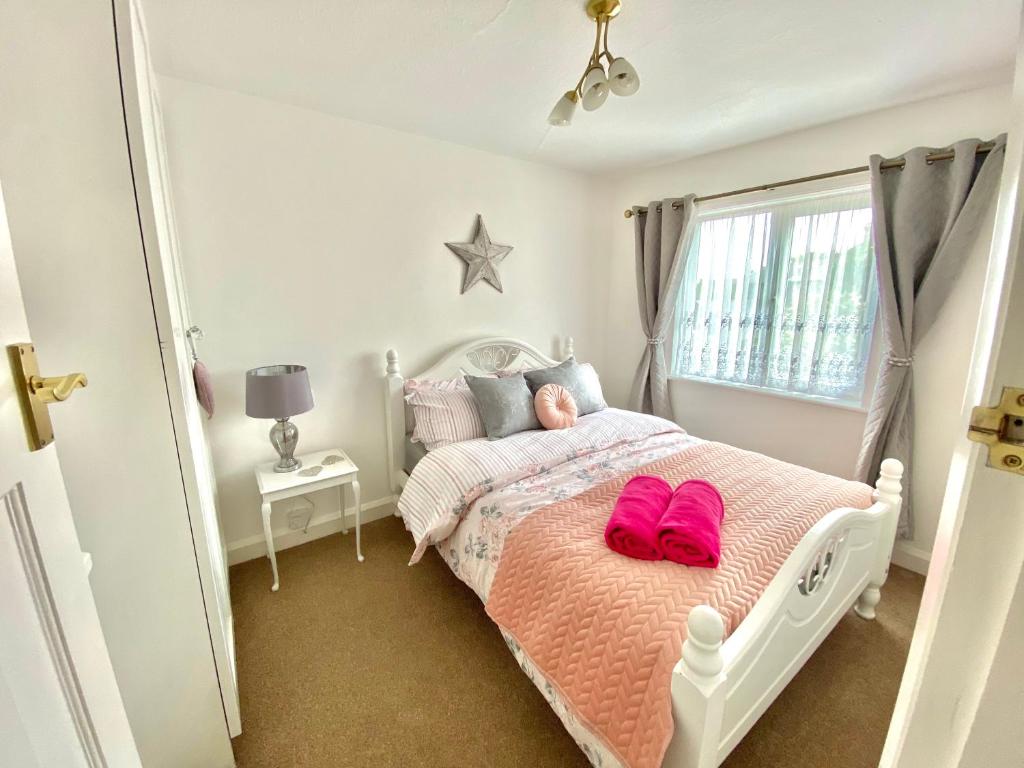 Un dormitorio con una cama con zapatos rosados. en Cosy Cottage Great Bentley near station and shops, en Great Bentley
