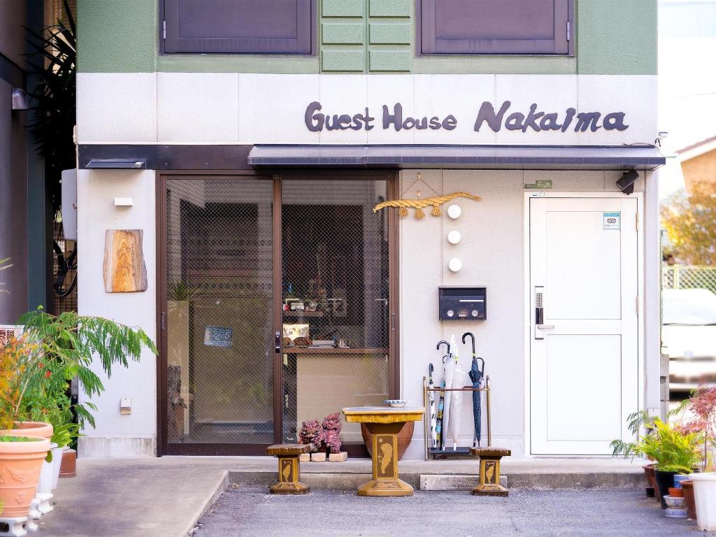 una pensión nairobi con una mesa frente a una tienda en Guest House Nakaima, en Fukuoka