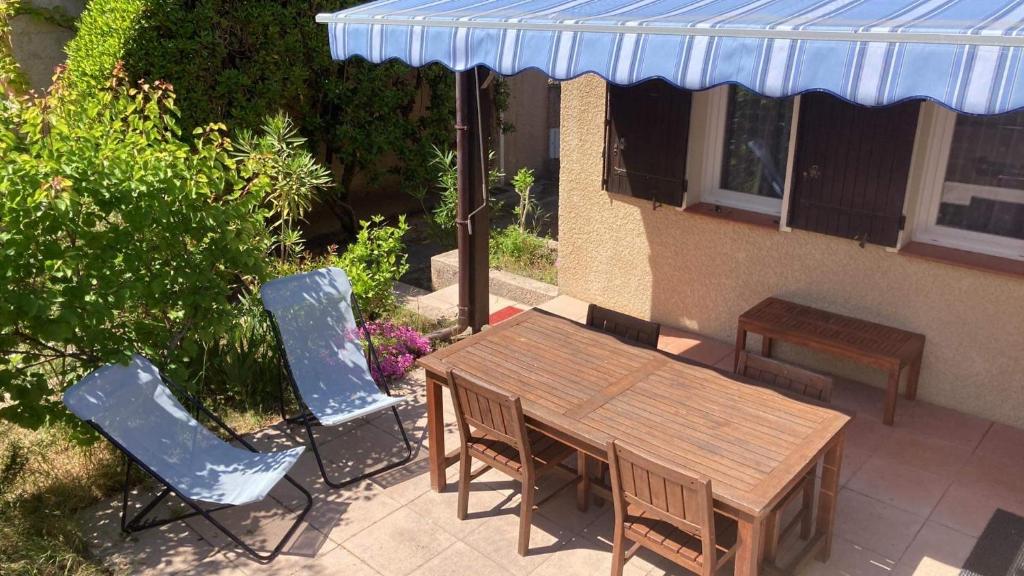 un patio con mesa de madera y sillas en Maison avec jardinet, piscine commune à Lacanau océan en Lacanau-Océan