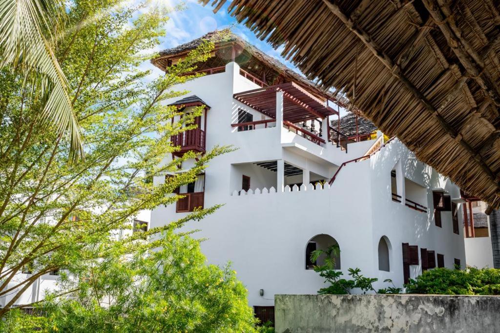 ein weißes Gebäude mit Bäumen davor in der Unterkunft Royal House Shela in Lamu