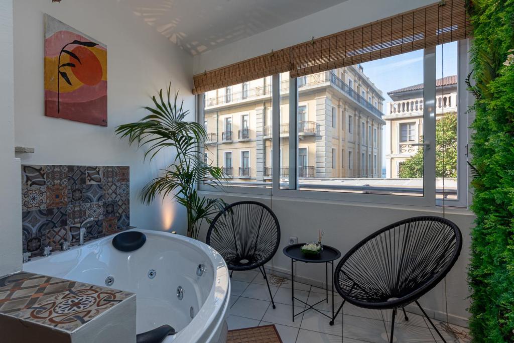 a bathroom with a tub and two chairs and a window at Kentia Modern/Artistic City Apartment in Heraklio